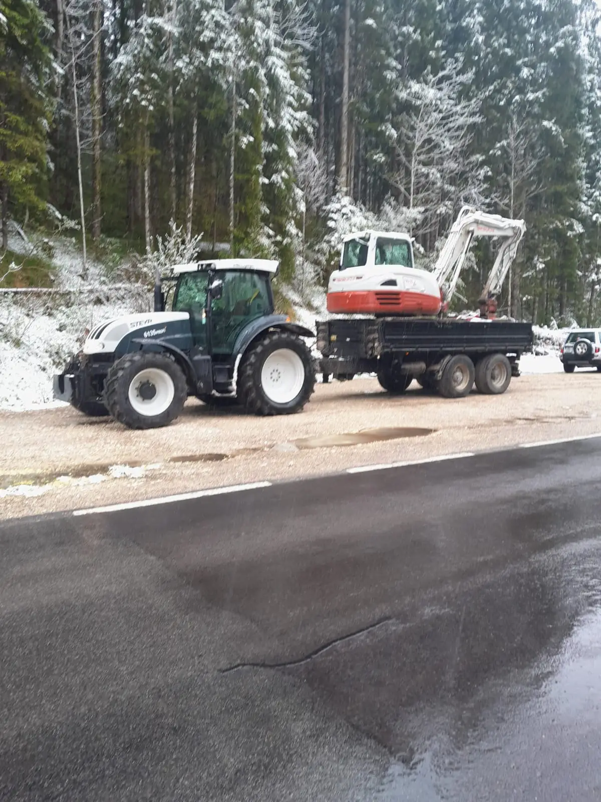 Traktor zieht Bagger auf Anhänger